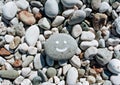 Stones on the beach with a blue sea and the inscription SMILE